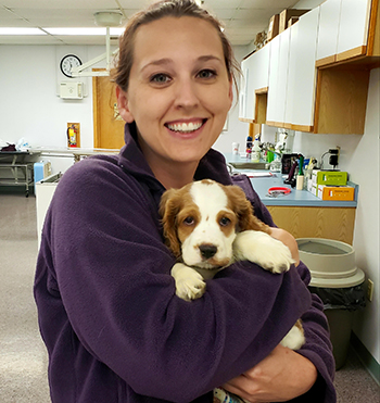 Veterinary technician, Emily Kimball, with a canine friend